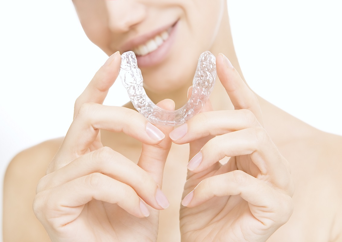 woman holding an invisible aligner